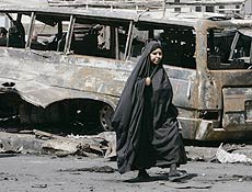 Iraquiana caminhando na frente de um carro bomba.
